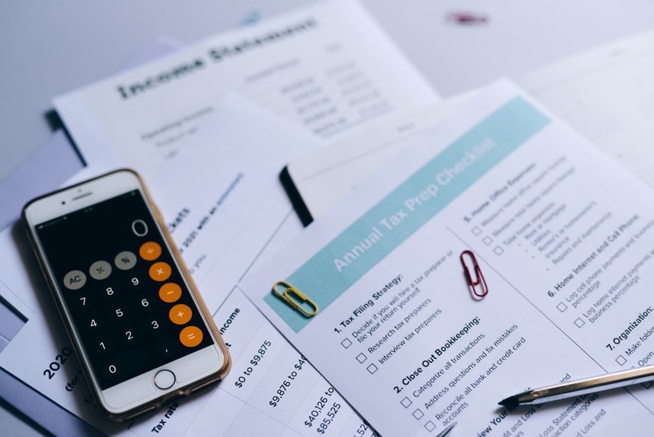 Mãos segurando documentos com gráficos financeiros e calculadora, simbolizando estratégia tributária